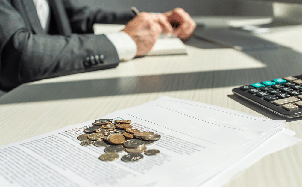 Cropped view of businessman writing in notebook near coins and petitions for bankruptcy on table, on