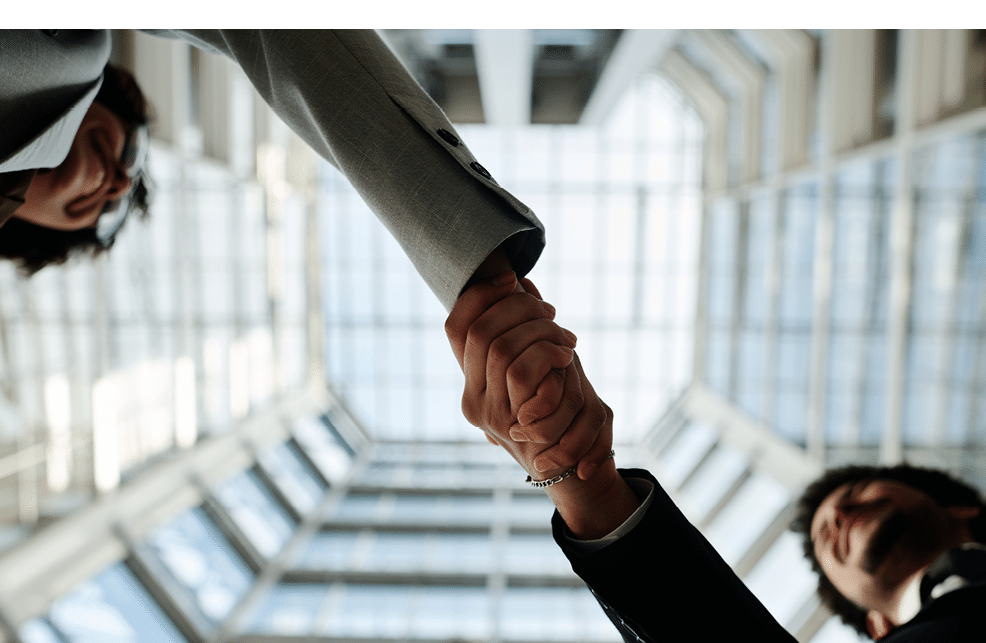 Low angle view of young business people shaking hands to each other standing in modern office building