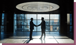 Two entrepreneurs handshaking in office center against window with sunlight penetrating inside
